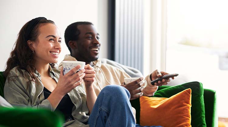 person smiling and pointing a tv remote 
