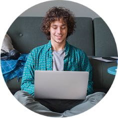 smiling child writing in front of a computer monitor